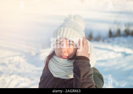 Jeune femme en blanc bonnet et écharpe en tricot sous la neige Banque D'Images