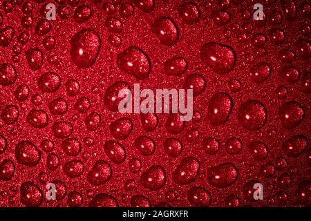 Un close up abstract macro photo de gouttelettes d'eau sur une poêle non stick gris avec un matériau gel flash rouge Banque D'Images