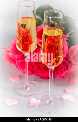 Libre de deux verres de champagne avec bouquet de roses roses en arrière-plan Banque D'Images