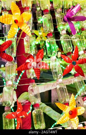 Close-up d'une décoration de Noël à partir de plastiques recyclés et des bouteilles vides avec des lumières de Noël vert à l'arrière-plan Banque D'Images