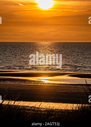 Colorée et ciel dramatique au-dessus de la mer et de la plage avec des roseaux en premier plan dans le nord de la France avant le coucher du soleil Banque D'Images