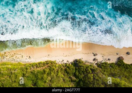 Vue de dessus, superbe vue aérienne d'une côte rocheuse avec une belle plage baignée par une mer agitée pendant le coucher du soleil, Plage Nyang Nyang, Bali, Indonésie. Banque D'Images