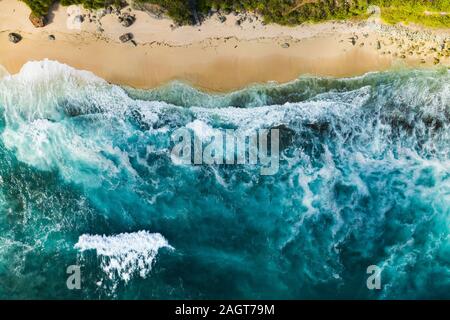 Vue de dessus, superbe vue aérienne d'une côte rocheuse avec une belle plage baignée par une mer agitée pendant le coucher du soleil, Plage Nyang Nyang, Bali, Indonésie. Banque D'Images