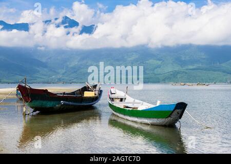 Les petits bateaux de pêche traditionnels au tour d'un lagon avec les montagnes au loin dans le Parc National de Bach Ma. Lang Co, Phu Loc, province de Thua Thien Hue, Vietnam, Asie Banque D'Images