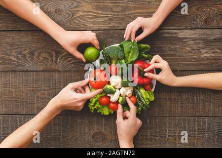 Les légumes crus, le holding de la famille sur la plaque avec des aliments sains Banque D'Images