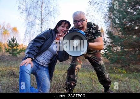 Un homme et une femme crier dans la forêt à travers un mégaphone. Amplificateur de son Banque D'Images