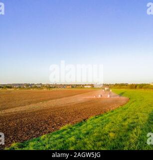 Une belle soirée d'été sur la terre campagne, dans les champs d'herbe et de terre labourée au coucher du soleil dans l'arrière-plan. Banque D'Images