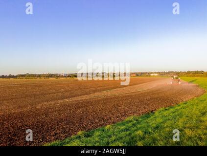 Une belle soirée d'été sur la terre campagne, dans les champs d'herbe et de terre labourée au coucher du soleil dans l'arrière-plan. Banque D'Images