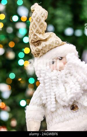 Funny Santa gnome jouet avec barbe blanche sur fond flou de couleurs des lumières d'arbre de Noël. Banque D'Images