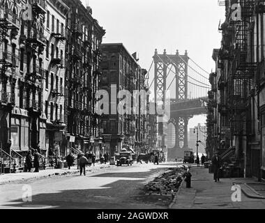 En regardant vers la Rue du Brochet le pont de Manhattan, la moitié de la rue dans l'ombre, gravats dans les caniveaux, une partie du trafic. Pike et Henry Rues, Manhattan. ca. 1936 Banque D'Images