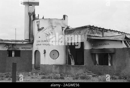 1947 - la ruine d'un bâtiment incendié de graffitis. Démarrer avec croix nazi (croix gammée) sur le dos de femme avec enfant. Texte : Djika Djangan Mendjadjah et Blanda, entre autres. - Emplacement : Indonésie, Java, Indes néerlandaises Banque D'Images