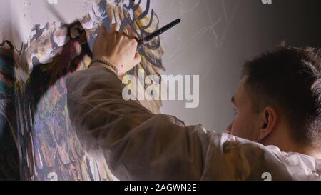 Concepteur de l'artiste dessine un aigle sur le mur. Décorateur artisan photo peintures à l'acrylique couleur d'huile. Peintre peintre vêtu de couche de peinture. À l'intérieur. Banque D'Images