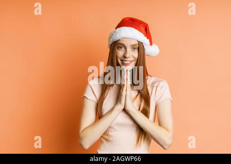 Rousseur caucasienne redhead woman praying geste, gardant paumes ensemble, demandant à copain avec regard suppliant à réaliser son rêve, d'acheter une Banque D'Images