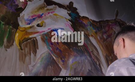 Concepteur de l'artiste dessine un aigle sur le mur. Décorateur artisan photo peintures à l'acrylique couleur d'huile. Peintre peintre vêtu de couche de peinture. À l'intérieur. Banque D'Images