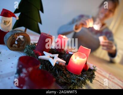 Garmisch Partenkirchen, en Allemagne. Dec 22, 2019. ILLUSTRATION - Une femme allume la quatrième bougie sur la couronne de l'Avent sur la quatrième apparition. Credit : Angelika Warmuth/dpa/Alamy Live News Banque D'Images