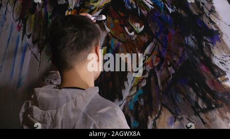 Concepteur de l'artiste dessine un aigle sur le mur. Décorateur artisan photo peintures à l'acrylique couleur d'huile. Peintre peintre vêtu de couche de peinture. À l'intérieur. Banque D'Images