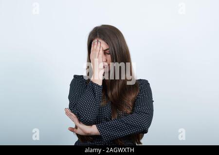 Femme malheureuse sur mur gris en gardant le doigt sur le front, à déçu Banque D'Images