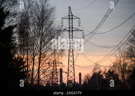 Selective focus photo. Belle vue à de puissants et d'énormes poteaux électriques haute tension, pendant le coucher du soleil. Banque D'Images