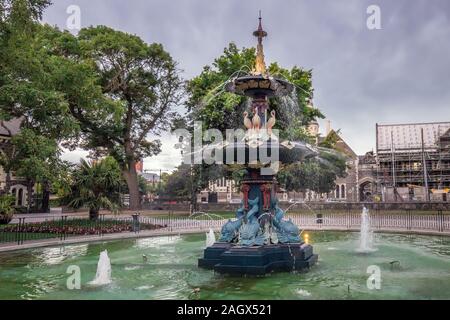 Pukaki, Nouvelle-Zélande - 25 décembre 2017 Le paon restauré fontaine dans les jardins botaniques de Christchurch au crépuscule avec l'ancien Centre des Arts Université Banque D'Images