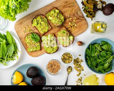 Des sandwichs avec de la guacamole avec les graines de citrouille et de semis de blé sur une planche en bois sur la table. Vue d'en haut. Banque D'Images