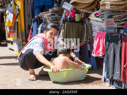 Vieux Marché Phsar Chas, Siem Reap Cambodge - Dame cambodgienne lave-petit enfant dans un bol en plastique en dehors du marché Banque D'Images