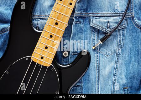 Black bass guitare avec jack cable sur veste jeans vintage pour la musique de fond. Concept de la jeunesse, de la musique ou rock star. Banque D'Images