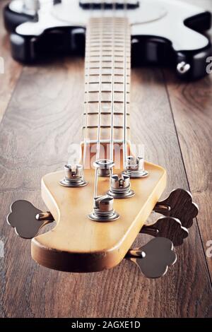 Vintage guitare basse électrique sur fond de table en bois. Vue depuis la disparition ou la tête du cou vers le haut du corps. Vue en gros plan. Banque D'Images