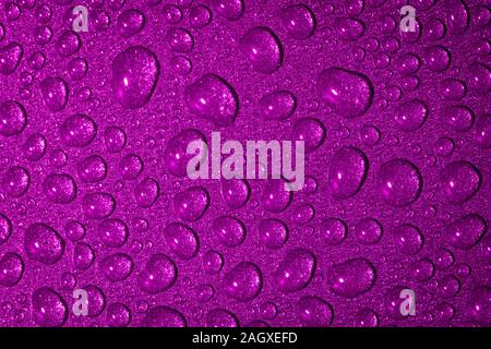Un close up abstract macro photo de gouttelettes d'eau sur une poêle non stick gris avec un matériau gel flash rose Banque D'Images
