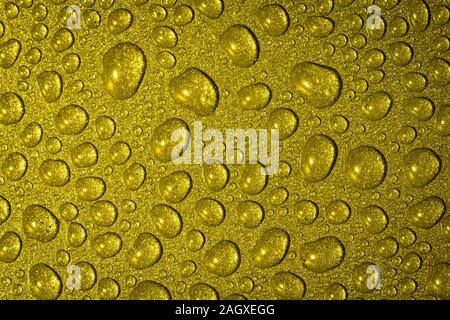 Un close up abstract macro photo de gouttelettes d'eau sur une poêle antiadhésive gris Matériau non éclairé avec une golden orange gel flash Banque D'Images