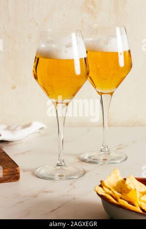 Bière en flûte, pils ou pilsner, avec chips de tortilla, fond clair et coloré Banque D'Images