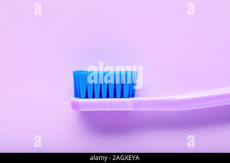 Close up vue latérale d'une nouvelle brosse à dents violet sur fond violet Banque D'Images