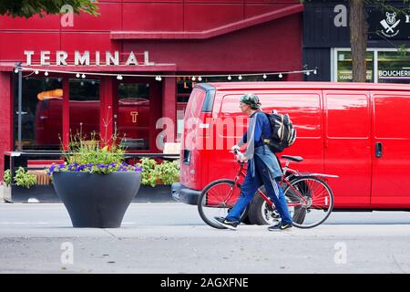 Montréal, Canada - Juin 2018 : Young man wearing sportswear marcher avec son vélo dans la rue à Montréal, Canada. Banque D'Images