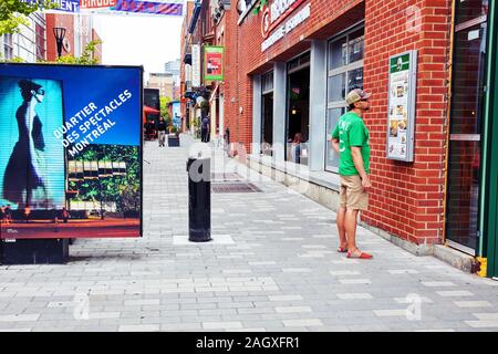 Montréal, Canada - Juin 2018 : Young man looking at les éléments de menu d'un restaurant sur la rue à Montréal, Québec, Canada. Banque D'Images