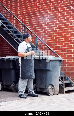 Montréal, Canada - Juin 2018 : African American cook d'un restaurant est d'avoir une pause cigarette à l'arrière-cour d'un restaurant à Montréal, Canada. Banque D'Images