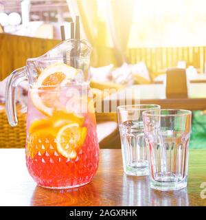 Pichet avec du jus d'orange et deux verres vides sont debout sur une table dans un café sur une chaude journée d'été,. Banque D'Images