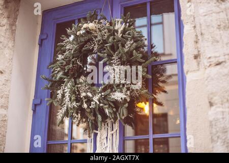 Couronne de Noël accroché à l'extérieur sur la porte en hiver faites de branches d'arbre, du décor, des ballons et des rubans, maison de vacances idée de conception Banque D'Images