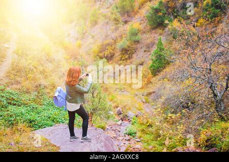 Female hiker prenant en selfies forêt montagnes. Touriste avec sac à dos est dans une gorge de montagne sous le coucher du soleil. Banque D'Images