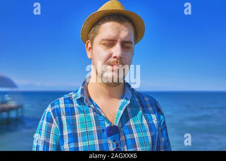 Guy de mettre la crème solaire sur le visage. L'homme à l'aide de Sun Bronzage Crème Corps de bloc sur la plage d'été. Banque D'Images