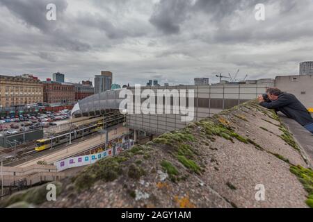 3007 tramway Metrolink Manchester au départ de Manchester Victoria en direction de l'est avec la ville derrière avec un photographe de prendre une photo Banque D'Images