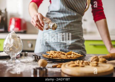 Faire cuire des cookies ménagère à la maison sur une cuisine colorée. Une femme tenant un besant d'or prêt avec biscuits fraîchement cuits au four en forme de Noël Banque D'Images