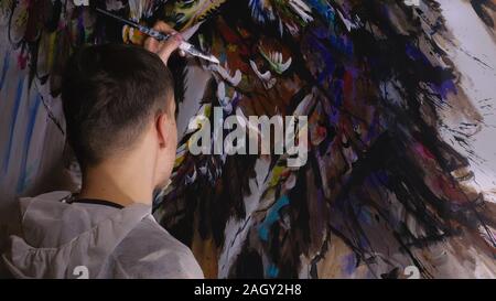 Concepteur de l'artiste dessine un aigle sur le mur. Décorateur artisan photo peintures à l'acrylique couleur d'huile. Peintre peintre vêtu de couche de peinture. À l'intérieur. Banque D'Images