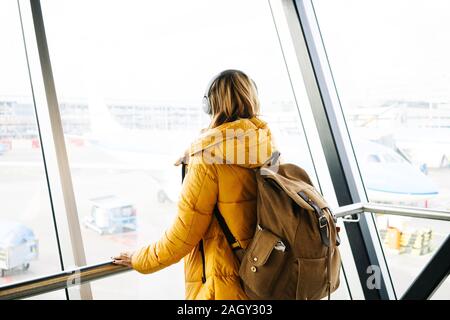Portrait d'une femme blonde se promène dans l'aéroport avec yellow jacket et son sac à dos Banque D'Images