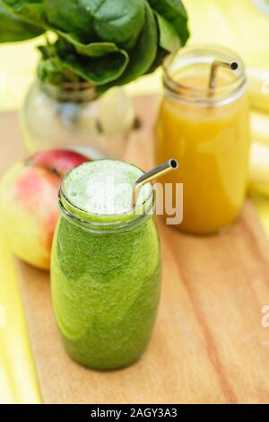 Smoothies aux fruits dans les pots de verre sur table jaune vert avec jardin flou en arrière-plan. Boisson d'été saine notion Banque D'Images