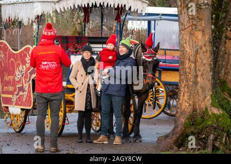 Souriant famille heureuse de trois posant pour la photo avec converti cheval de Noël tiré par le thème de calèche ou voiture de jaunisse à Killarney, en Irlande Banque D'Images