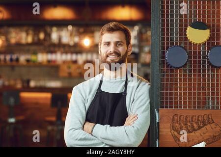 Smiling waiter barman barbu debout sur l'arrière-plan d'un restaurant pub bar. Banque D'Images