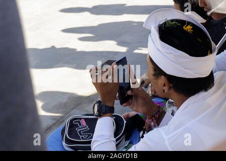 Bali, Indonésie. 20 Oct, 2019. Un homme prend une photo avec un morceau d'un miroir sombre sous l'appareil photo du smartphone aux portes du paradis à Bali.Chaque jour, des milliers de personnes se rassemblent et attendre leur tour pour prendre des photos au temple de Lempuyang à Bali. Le temple est devenu célèbre pour les photos prises à la ''Portes du ciel'' mais la photo se cache un secret. La réflexion de l'eau à vu dans les milliers de photos partagées sur les réseaux sociaux est fausse et manipulée. Credit : Hugo Amaral/SOPA Images/ZUMA/Alamy Fil Live News Banque D'Images