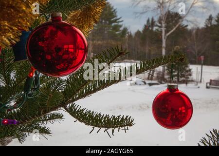 Boules de Noël et des ornements accroché à un arbre avec de la neige dans la distance. Fait une grande carte ou image d'arrière-plan. Banque D'Images
