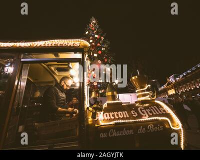 Strasbourg, France - Dec 24, 2018 : de l'homme adulte vente de châtaignes grillées de la traditionnelle voiture de train en Place Kleber à touristes et habitants lors du Marché de Noël annuel Banque D'Images