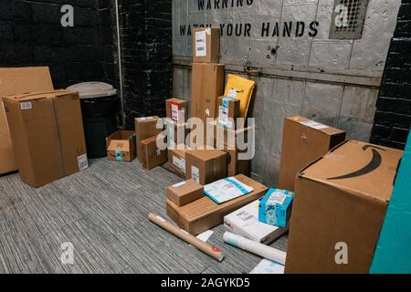 Amazon, FedEx et USPS autres forfaits livraison Vente en ligne d'être empilés recueillies auprès d'une salle de courrier appartement à Brooklyn, New York, USA Banque D'Images