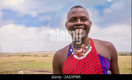 Un homme adulte membre de la tribu Masai au Kenya, le port du bijoux tribaux traditionnels et les vêtements de couleur rouge de la Masai. Banque D'Images